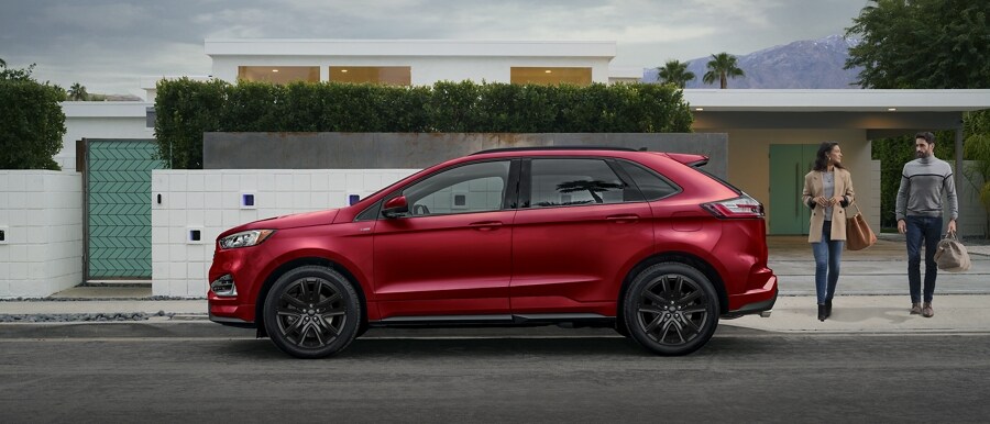 2024 Ford Edge® ST-Line model in Rapid Red parked in front of a modern home with a man and woman approaching