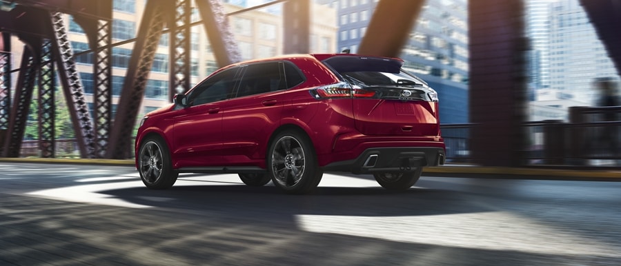2024 Ford Edge® ST-Line in Rapid Red being driven on a road with overpass in background