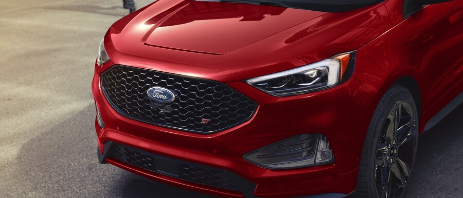 Grille and driver’s side headlamp of a 2024 Ford Edge® ST SUV in Rapid Red