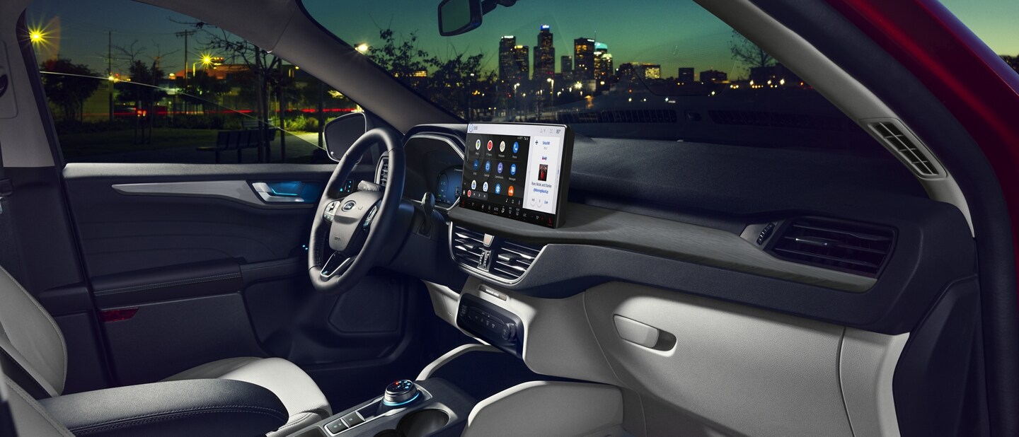 2023 Ford Escape® in Rapid Red at night, passenger side door open with cityscape in background