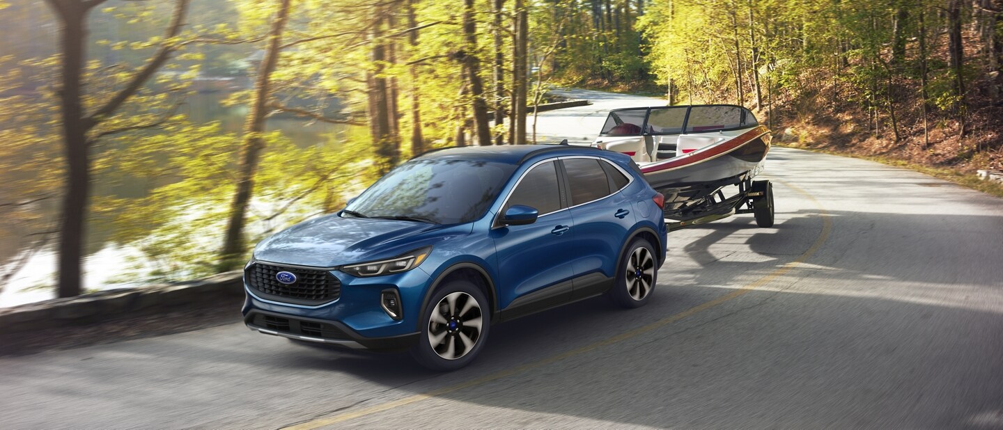 2023 Ford Escape® in Atlas Blue towing a boat along a river road