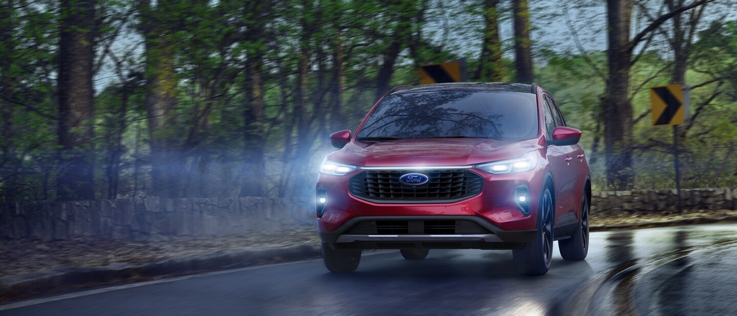 2023 Ford Escape® in Rapid Red Metallic Tinted Clearcoat being driven down a dark wet road