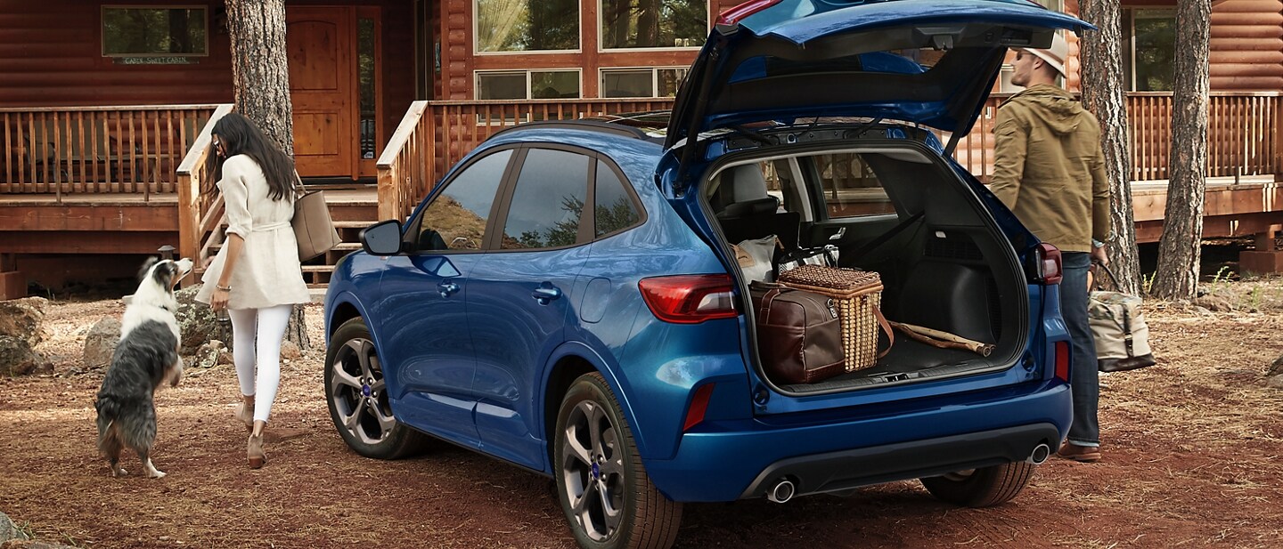 2023 Ford Escape® in Atlas Blue parked in front of cabin woman unloading luggage