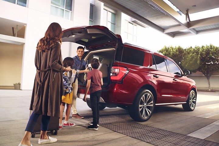 Family unloading cargo from rear of 2021 Ford Expedition in Rapid Red Metallic Tinted Clearcoat