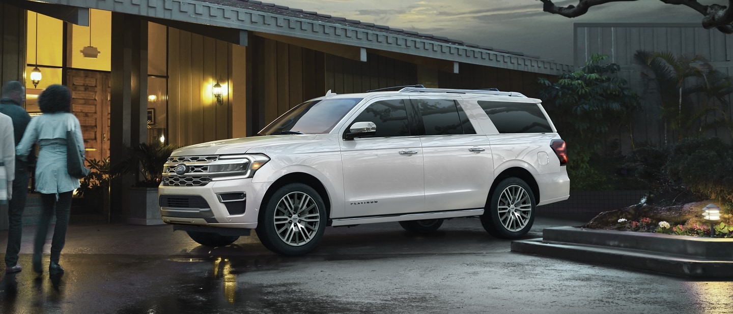 Four people approaching a 2023 Ford Expedition SUV parked in front of a home
