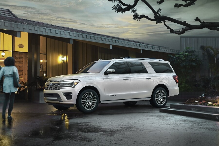 Four people approaching a 2023 Ford Expedition SUV parked in front of a home