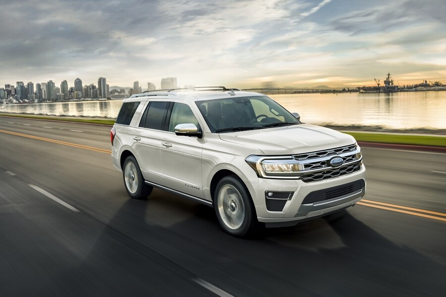 A 2023 Ford Expedition being driven on a highway near water with the city in the background