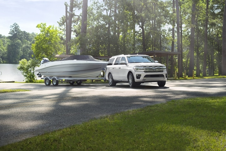 A 2023 Ford Expedition SUV towing a boat at a boat launch
