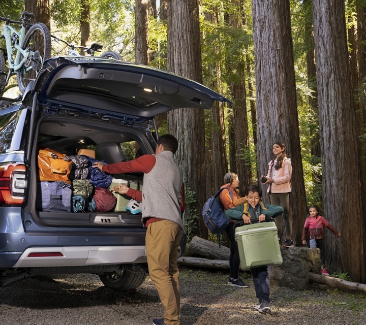 A family unloading gear from a 2023 Ford Expedition SUV parked in the woods