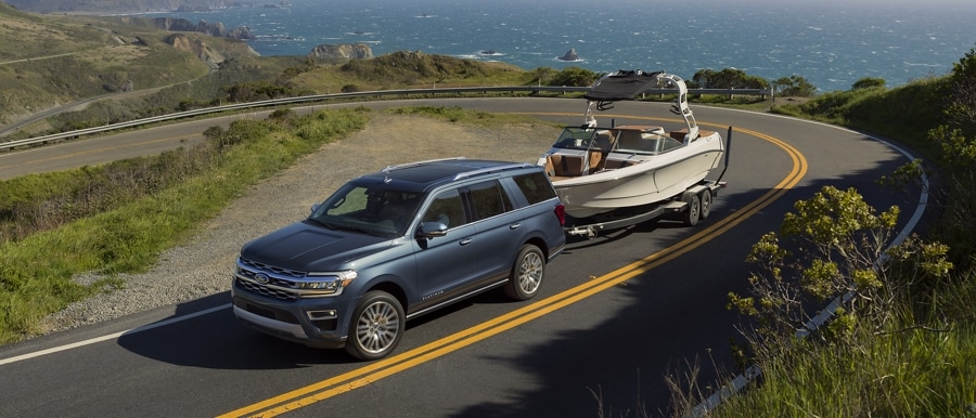 A 2023 Ford Expedition SUV towing a boat up a hill