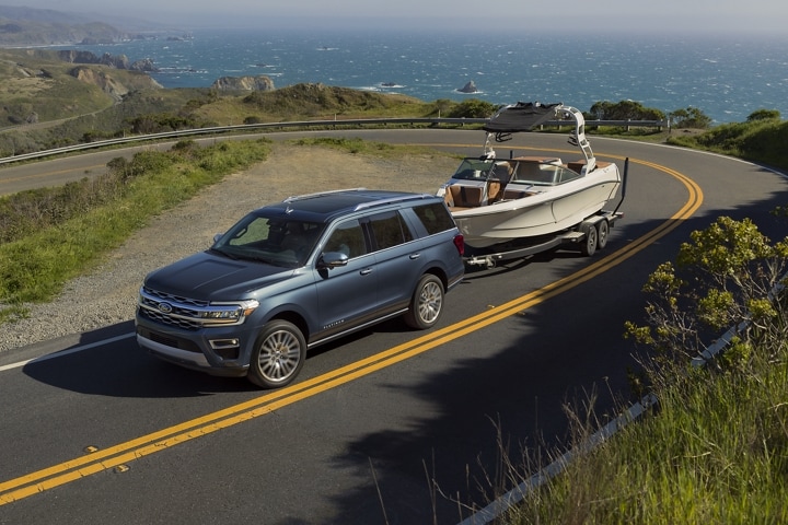 A 2023 Ford Expedition SUV towing a boat up a hill
