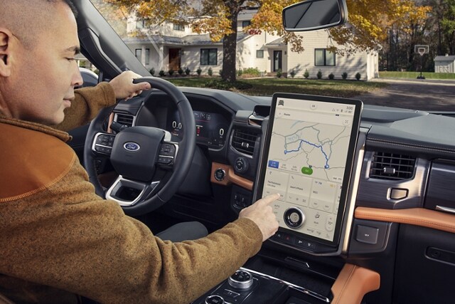 Man sitting in driver seat using SYNC® 4 on available 15.5” display screen
