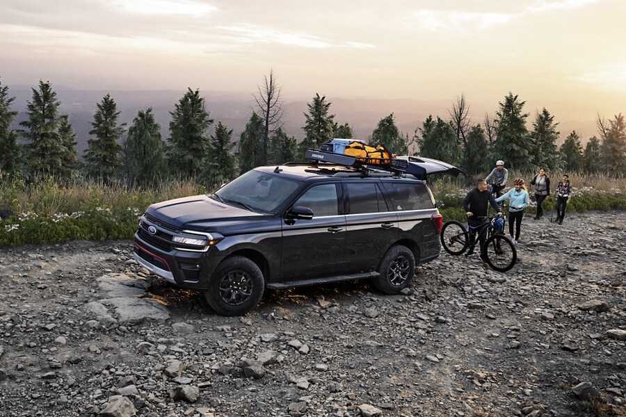 A 2023 Ford Expedition SUV parked on a rocky road near a body of water