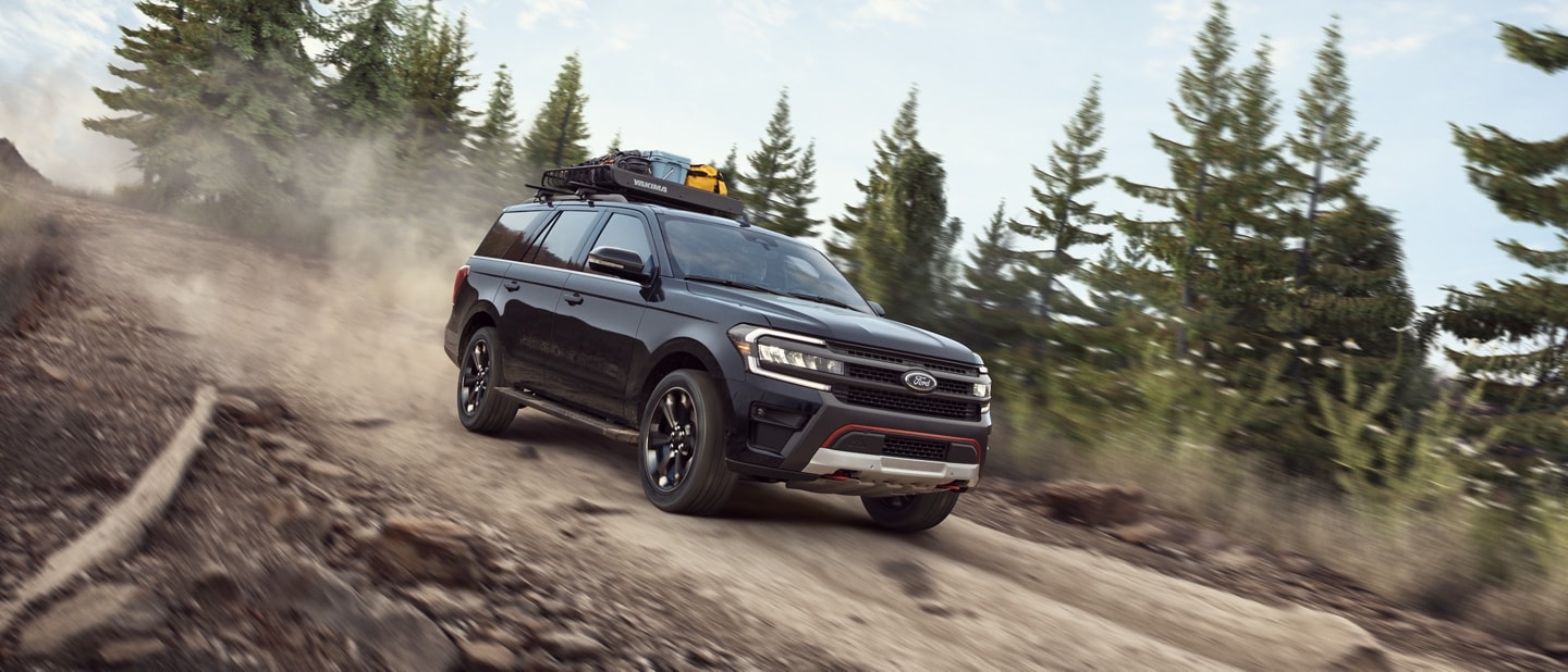 A 2023 Ford Expedition SUV being driven down a forest dirt road