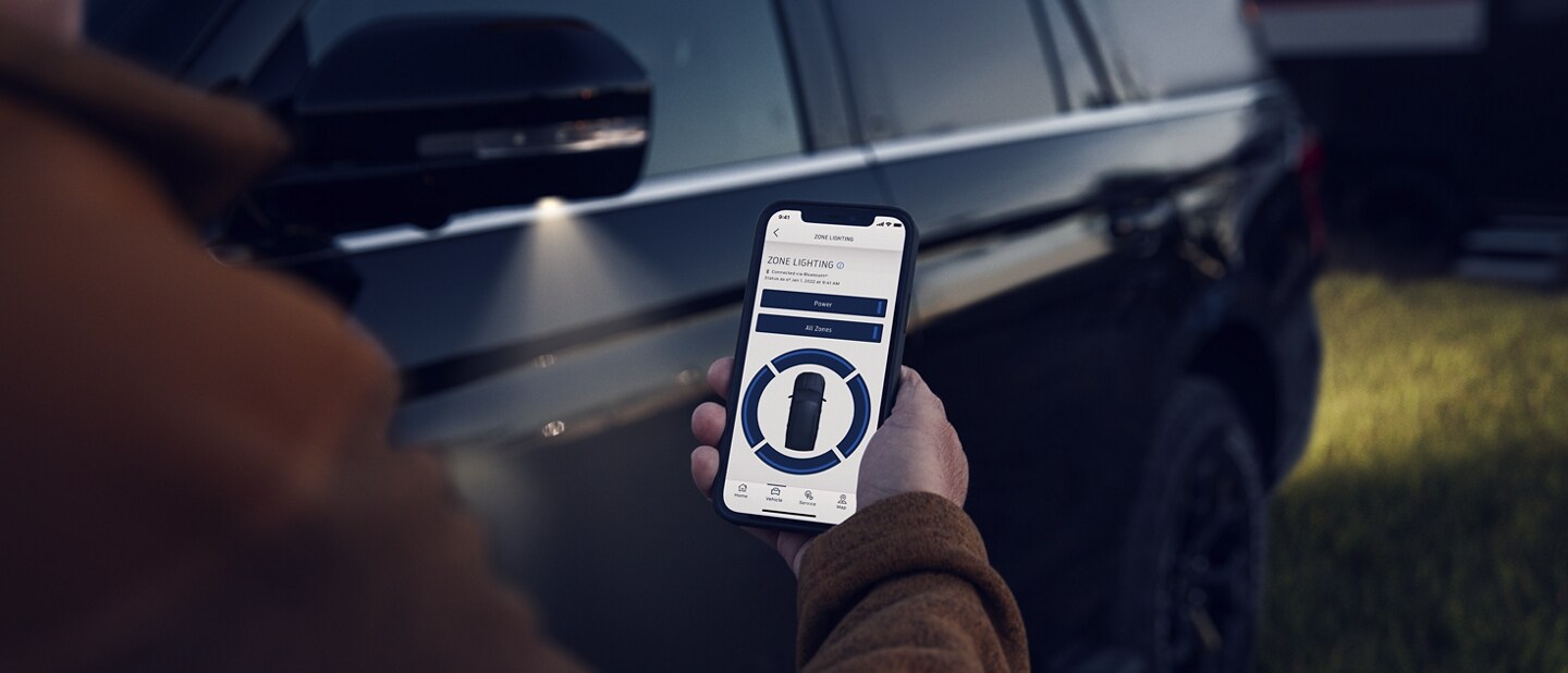 A person controlling Exterior Zone Lighting with their smartphone
