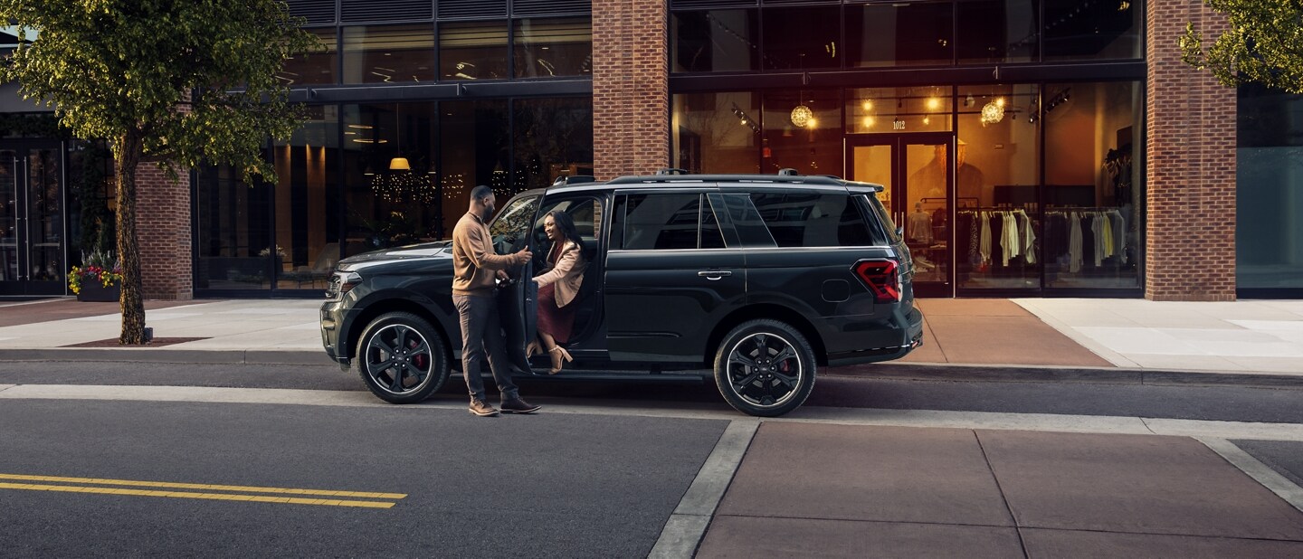 A man opening the door of a 2023 Ford Expedition SUV as a woman exits