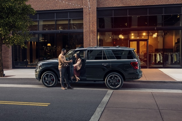 A man opening the door of a 2023 Ford Expedition SUV while a woman exits
