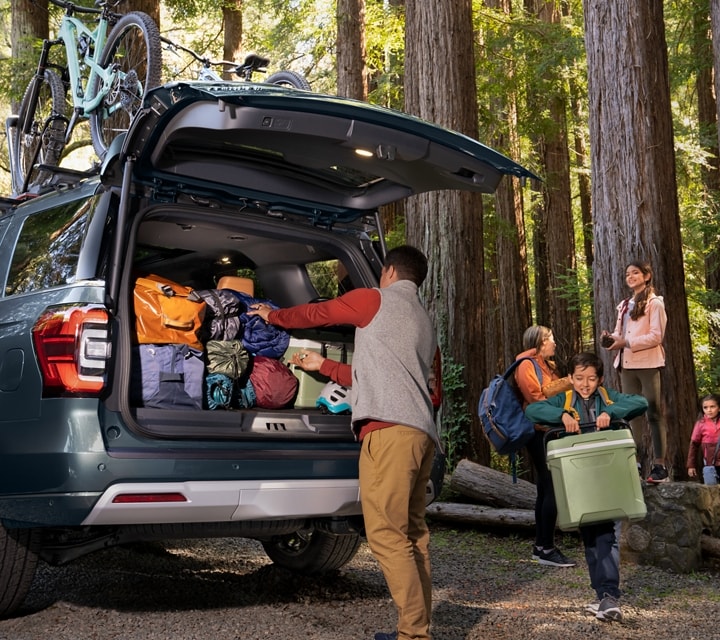 A family unloading gear from a 2024 Ford Expedition SUV parked in the woods