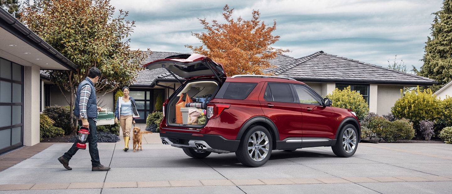 2023 Ford Explorer® Platinum model parked in a driveway with rear hatch open with two people and a dog approaching