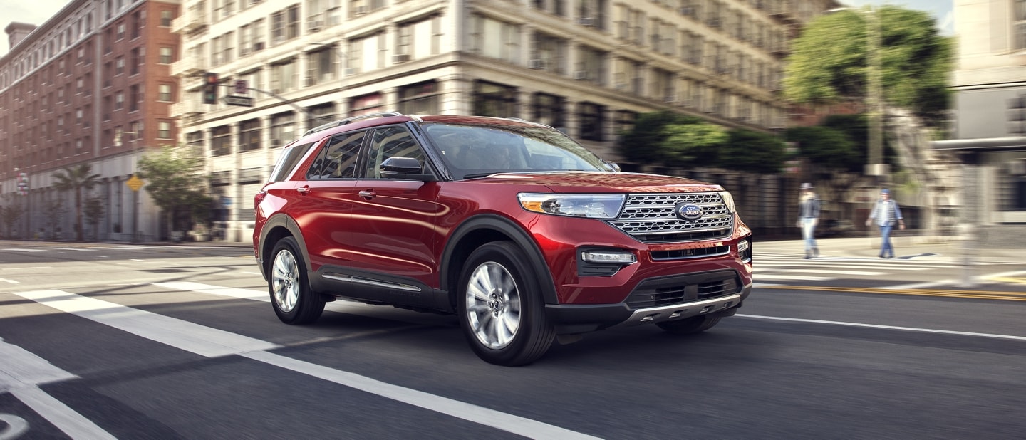 2023 Ford Explorer® Limited model in Rapid Red Metallic Tinted Clearcoat being driven down a city street