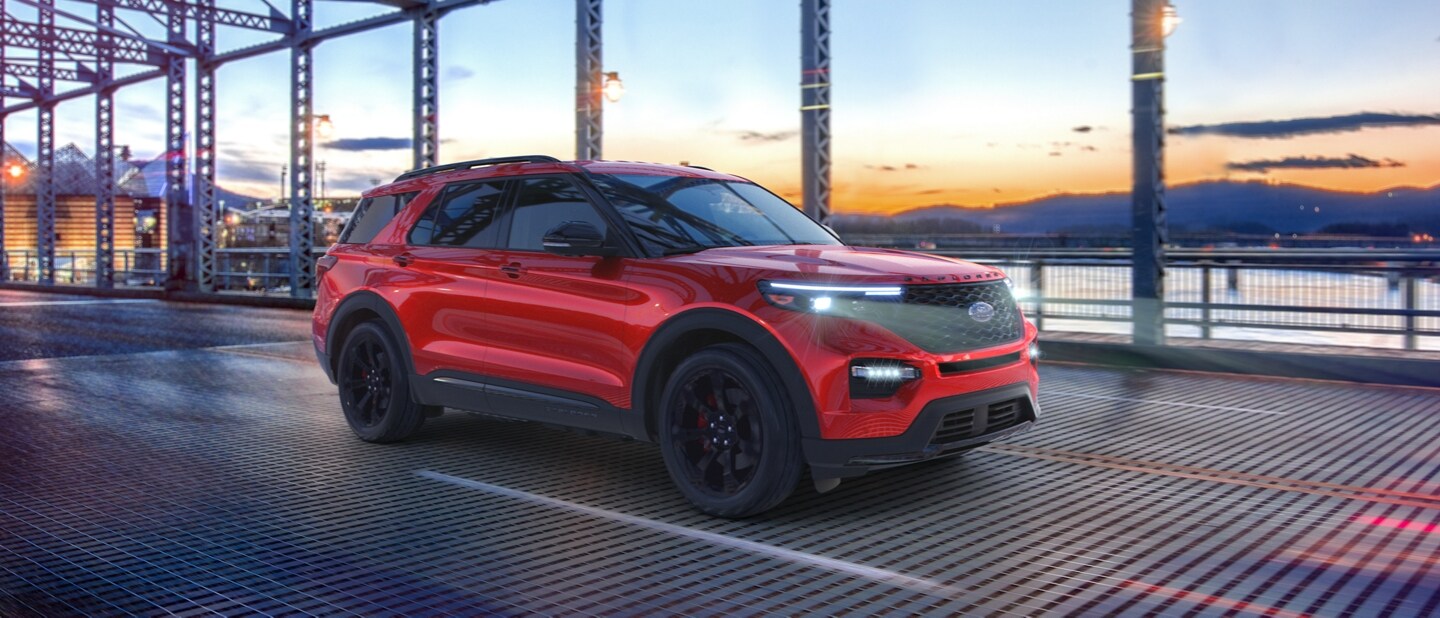 2023 Ford Explorer® ST model in Rapid Red Metallic Tinted Clearcoat being driven across a bridge