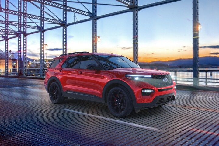 2023 Ford Explorer® ST model in Rapid Red Metallic Tinted Clearcoat (extra cost colour option) being driven across a bridge