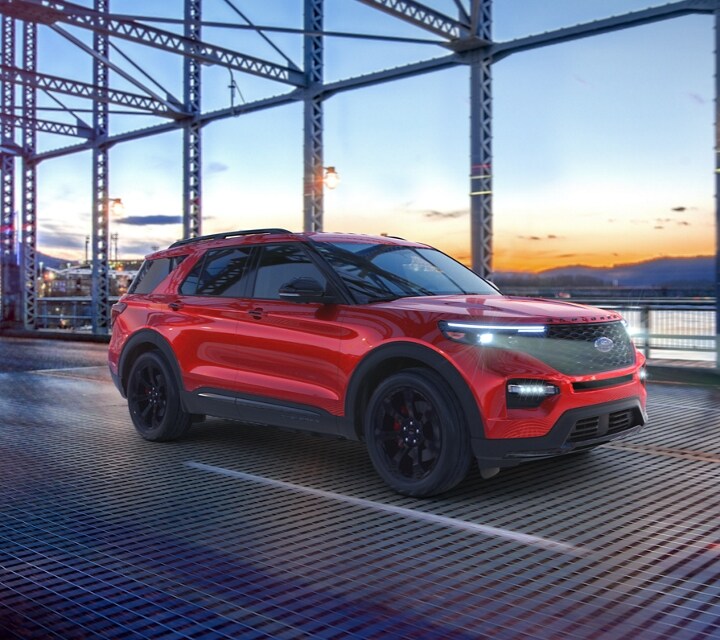 2023 Ford Explorer® ST model in Rapid Red Metallic Tinted Clearcoat (extra cost colour option) being driven across a bridge