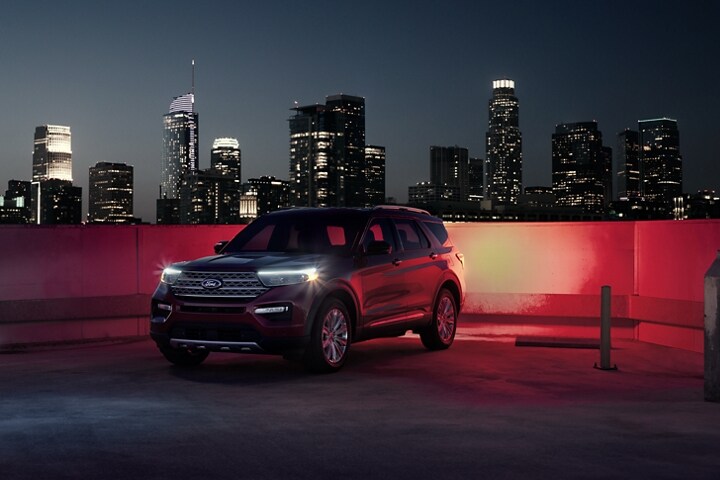 2023 Ford Explorer® Limited Hybrid SUV on top of a parking structure at night with a cityscape in the background