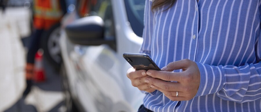 Person uses a smartphone while a technician repairs a tire on their vehicle