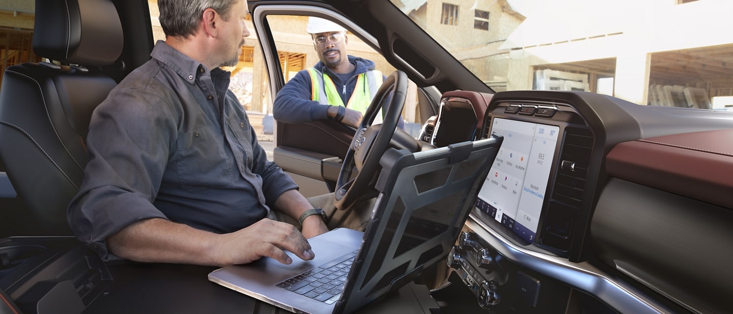 A man in a parked 2021 Ford F 1 50 using his laptop