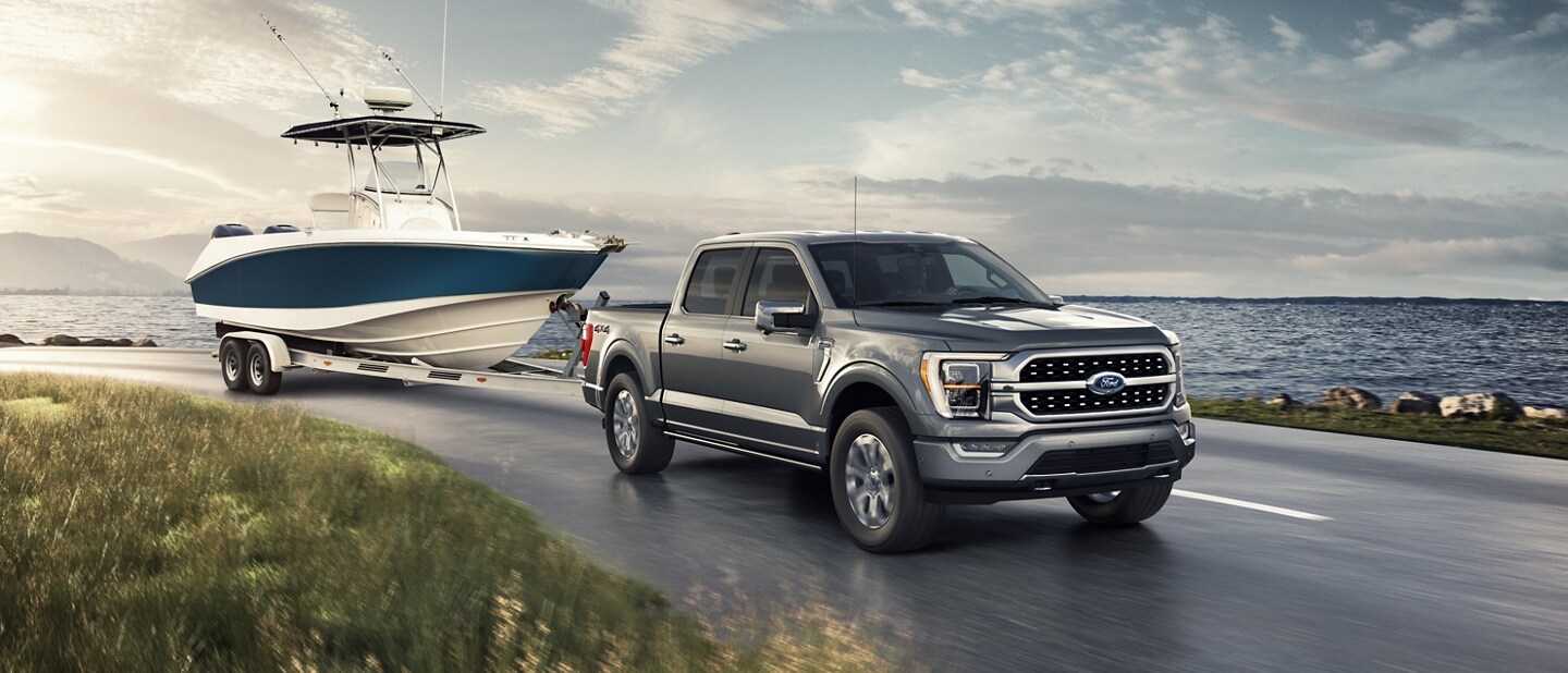 A 2023 Ford F-150® pickup towing a boat next to a lake