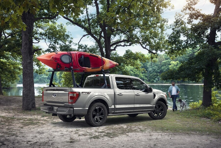 2023 Ford F-150® in Iconic Silver parked near a lake with a kayak mounted to a Ford Accessories Kayak Rack