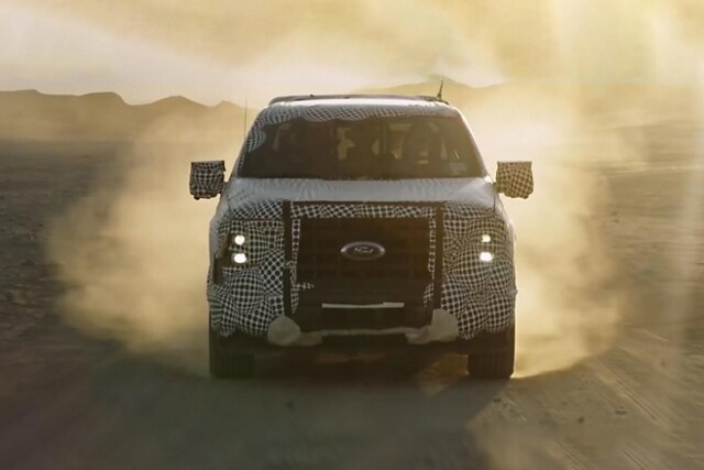 Front view of a disguised 2023 Ford F-150® PowerBoost™ hybrid being driven off-road in the desert