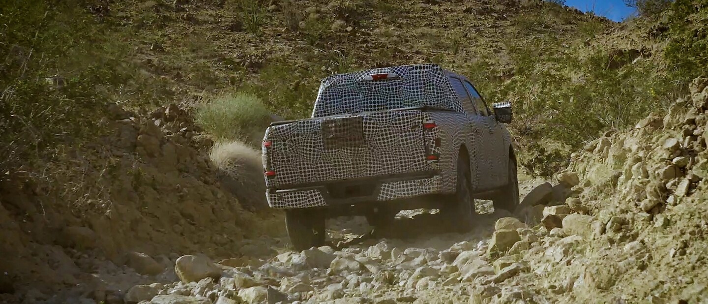 2023 Ford F-150® covered in disguise wrap off-roading through a desert gully