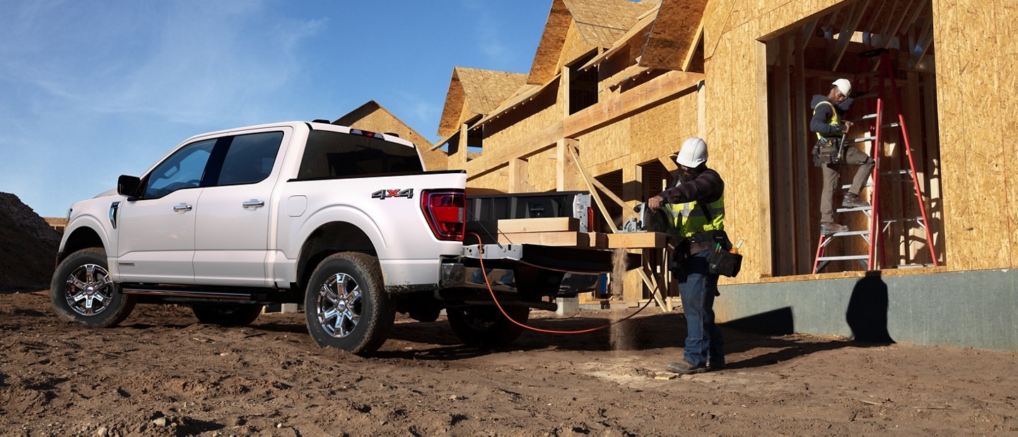 A man cutting wood on the tailgate of a 2023 Ford F-150®