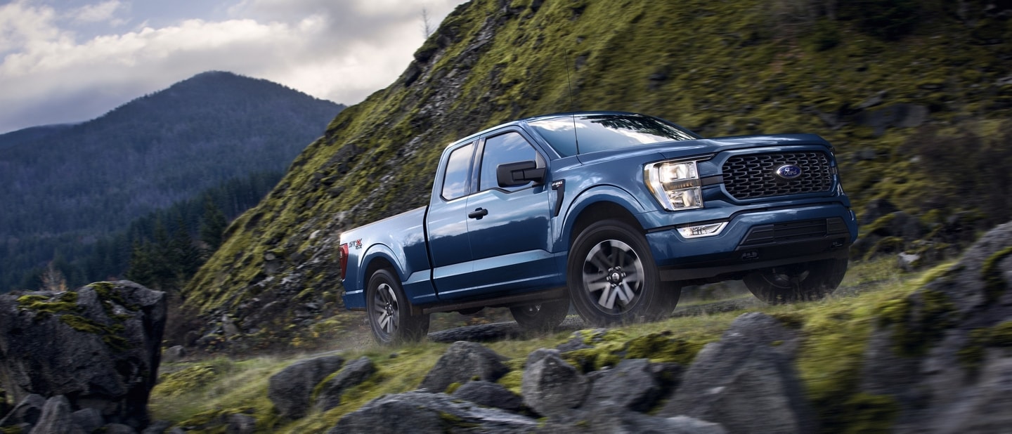 2023 Ford F-150® XLT pickup in Atlas Blue being driven on a mountain road