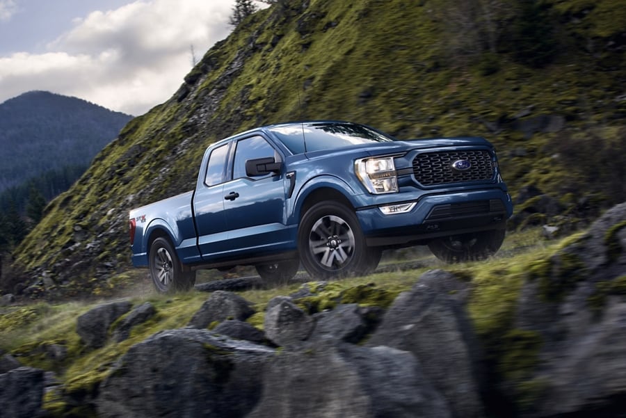 2023 Ford F-150® XLT pickup in Atlas Blue being driven on a mountain road