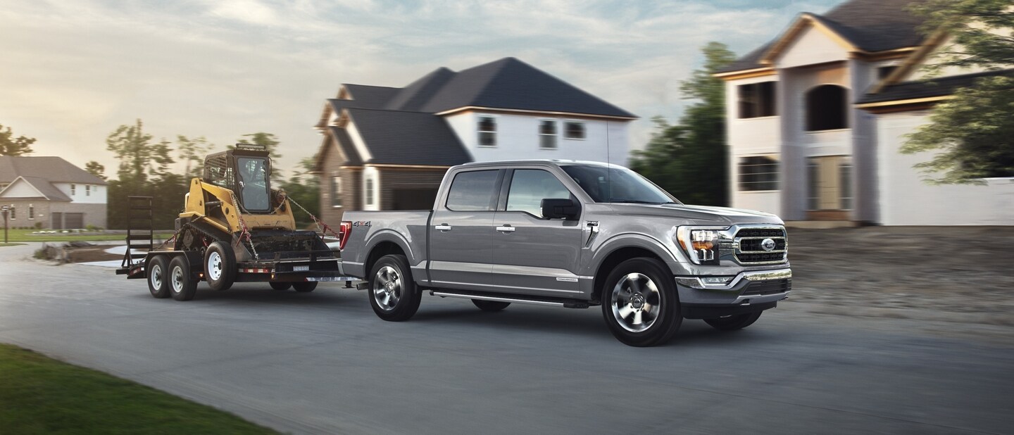 A 2023 Ford F-150® truck towing a backhoe on a trailer