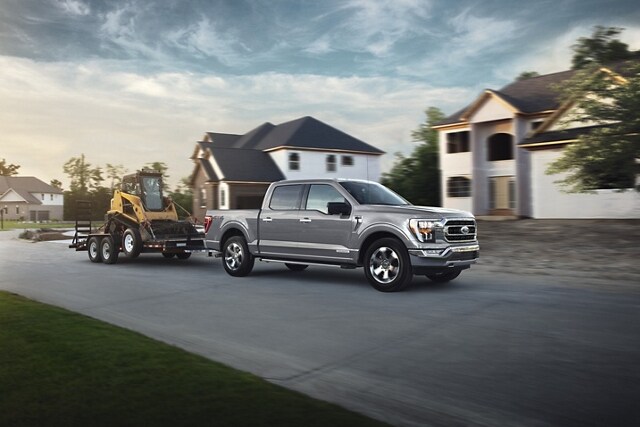 A 2023 Ford F-150® truck towing a backhoe on a trailer