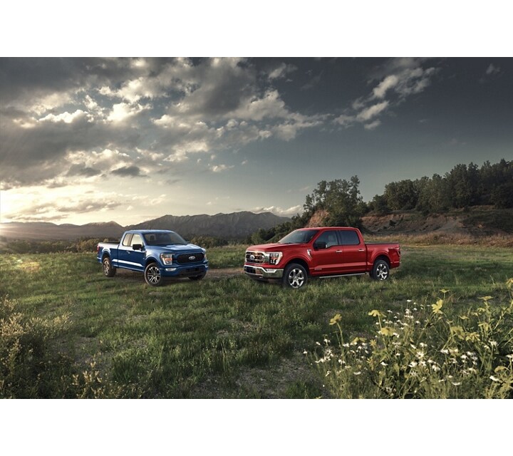 2023 Ford F-150® XL in Atlas Blue and F-150® XLT in Race Red parked on a mountain overlook