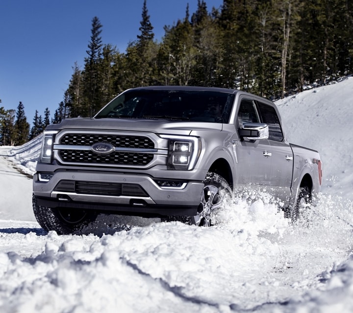 2023 Ford F-150® shown in Iconic Silver driving down a snowy road