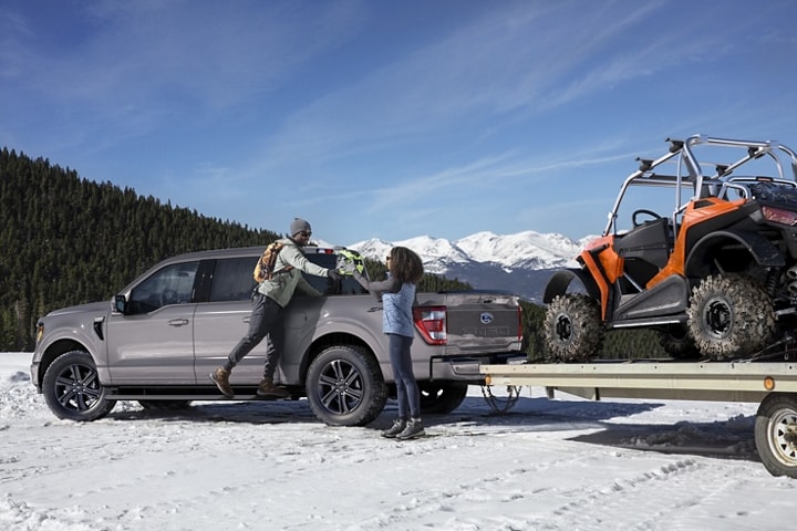 Two people near a 2023 Ford F-150® in the snow