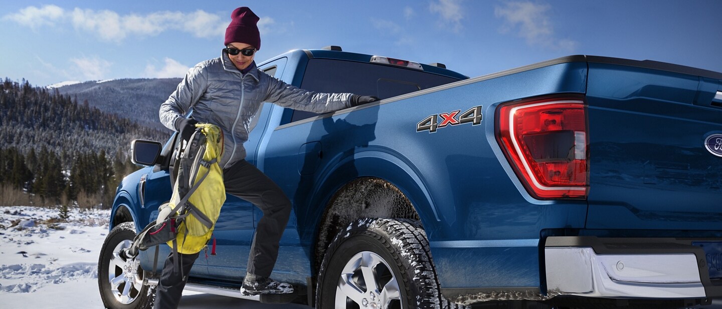 A person using the sidestep to put gear into the bed of the 2023 Ford F-150® pickup