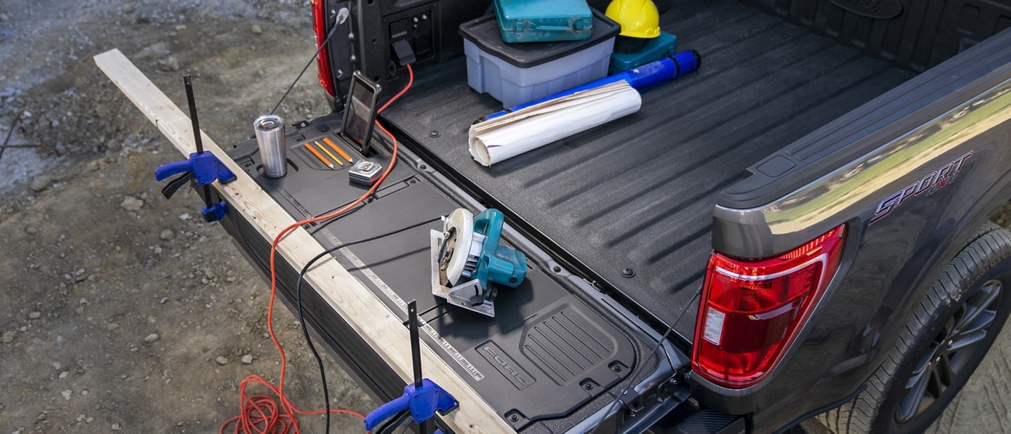 Tailgate and bed area of a 2023 Ford F-150® pickup with power tools plugged into the Pro Power Onboard outlets
