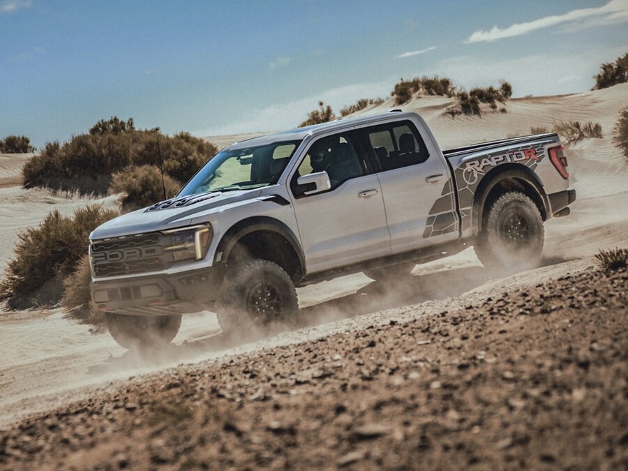 2024 Ford F-150® Raptor® being driven off-road in the desert kicking up dust