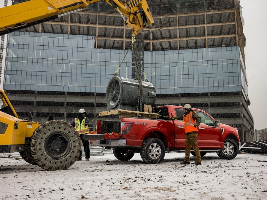 Person standing behind a 2024 Ford F-150® pickup while a giant turbine motor is being lowered into the truck bed