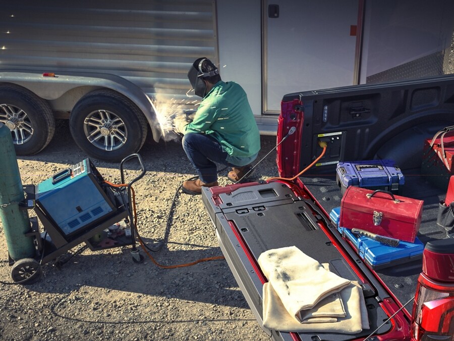 Man using a TIG welder that's plugged into the Pro Power Onboard feature located in the truck bed