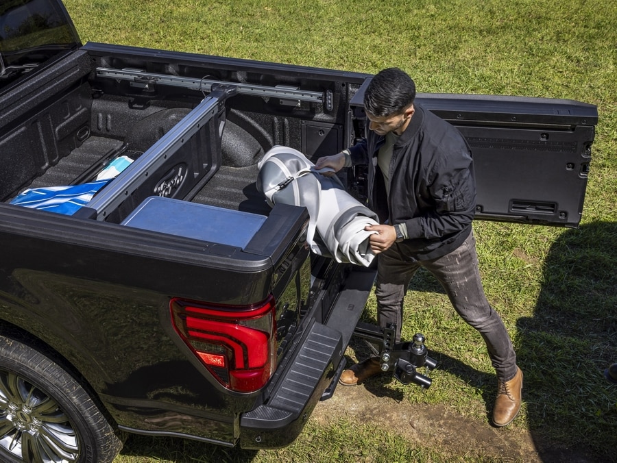 Person using the Pro-Access Tailgate while unloading gear from the truck bed of a 2024 Ford F-150® pickup