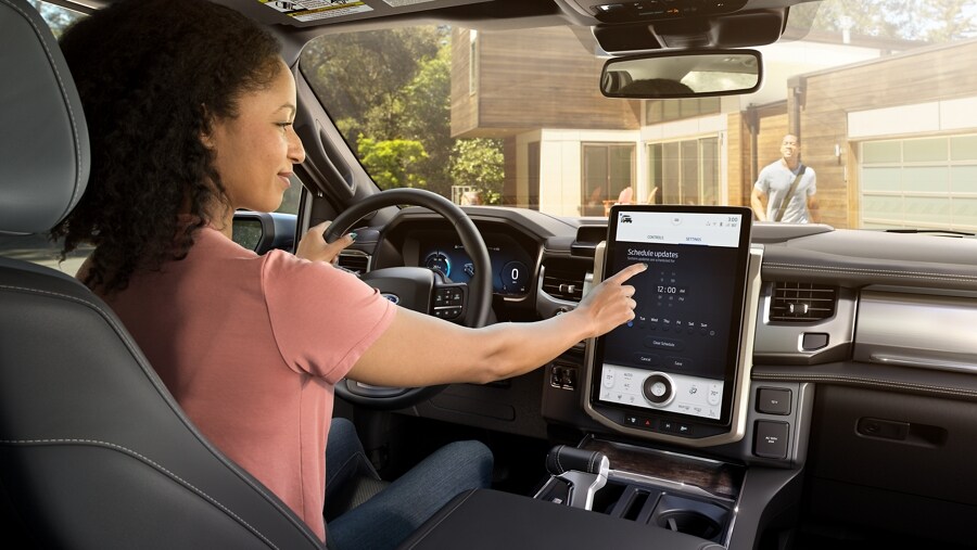 Interior of 2023 Ford F-150® Lightning® showing a woman using the touchscreen controls of the large centre display