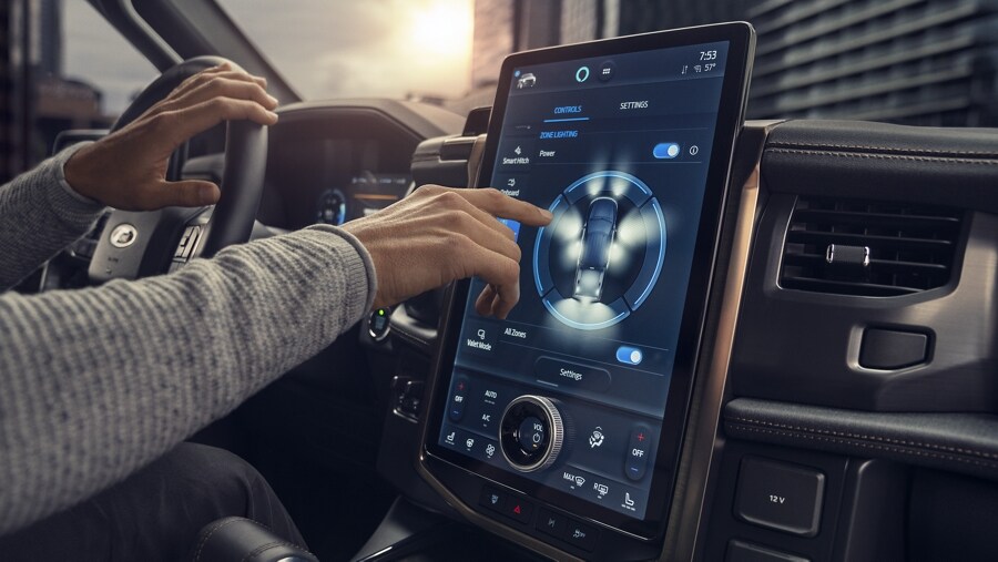 Interior image of the large centre display screen and man holding the steering wheel of the 2023 Ford F-150® Lightning®